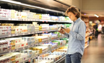 Teenager shopping in supermarket, reading product information