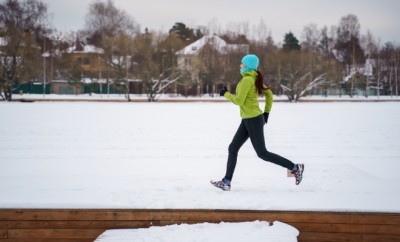 Photo of young athlete woman running in winter park in afternoon