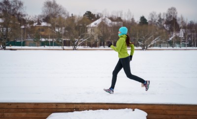 Photo of young athlete woman running in winter park in afternoon