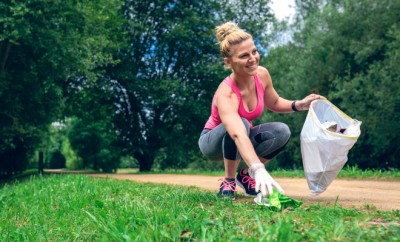 Girl crouching with bag picking up trash doing plogging