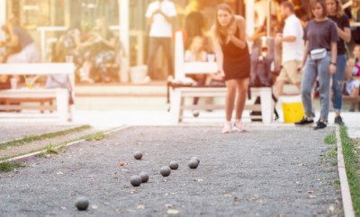 Girls playing petanque against retro style cafe on a sunset