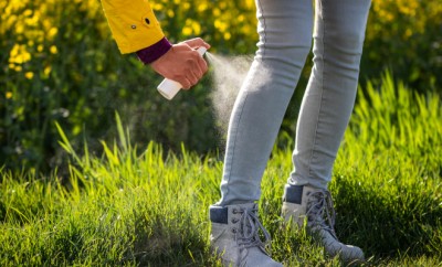 Spraying insect repellent on legs and boots. Protection against