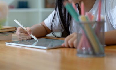 Cropped shot of girl relaxing with mock-up digital tablet on wooden worktable after finish her homework