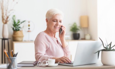 Senior business woman working from home, discussing project with client, using laptop, panorama with empty space