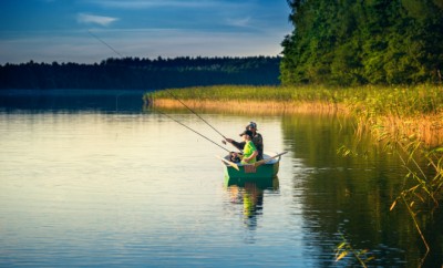 father and son catch fish from a boat at sunset