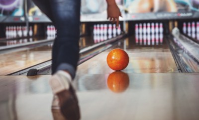Woman in club for bowling is throwing ball.