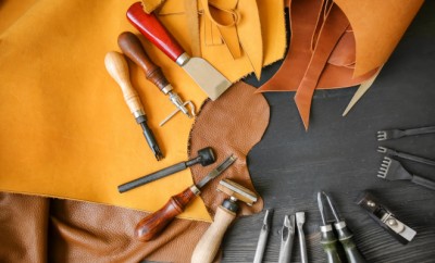 Leather with craft tools on dark wooden background