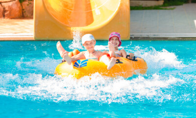 Cute happy girls in amusment aquapark. Summertime, vacation concept.